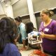 A woman holds a Sea Perch ROV and talks to people at an information table