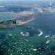 An aerial shot of a blue-green Massachusetts Bay and Castle Island with many boats and a couple of tall ships