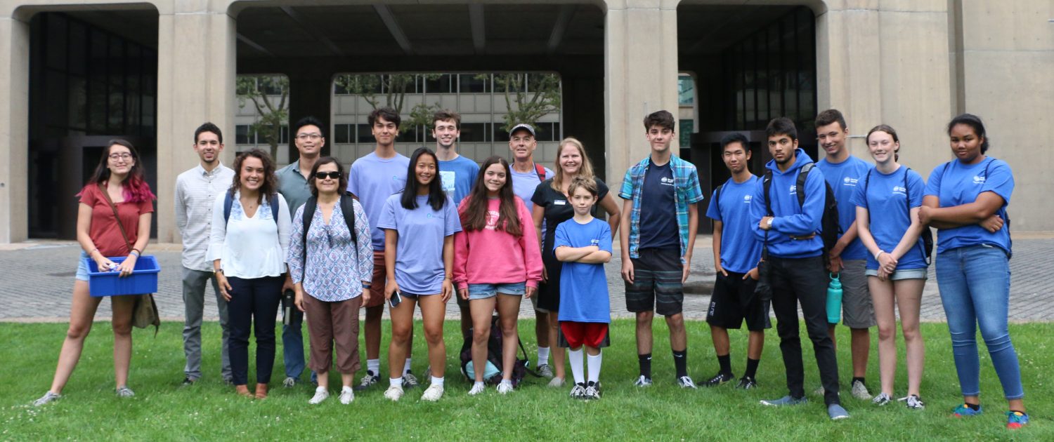 A group of about 20 researchers, citizen scientists, and student outside of the MIT EAPS building.