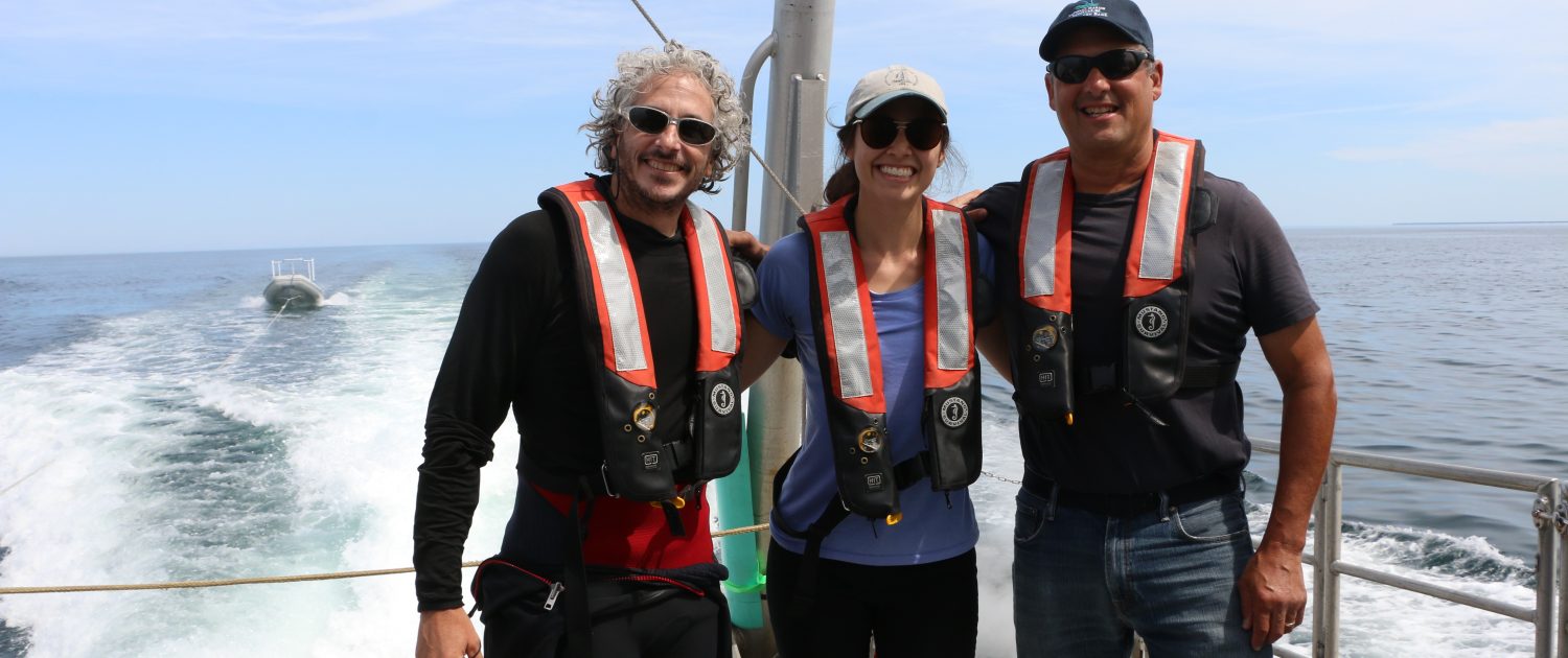 Underwater photographer Keith Ellenbogen stands on the back of a boat with a Knauss Fellow and the superintendent of Stellwagen Bank.