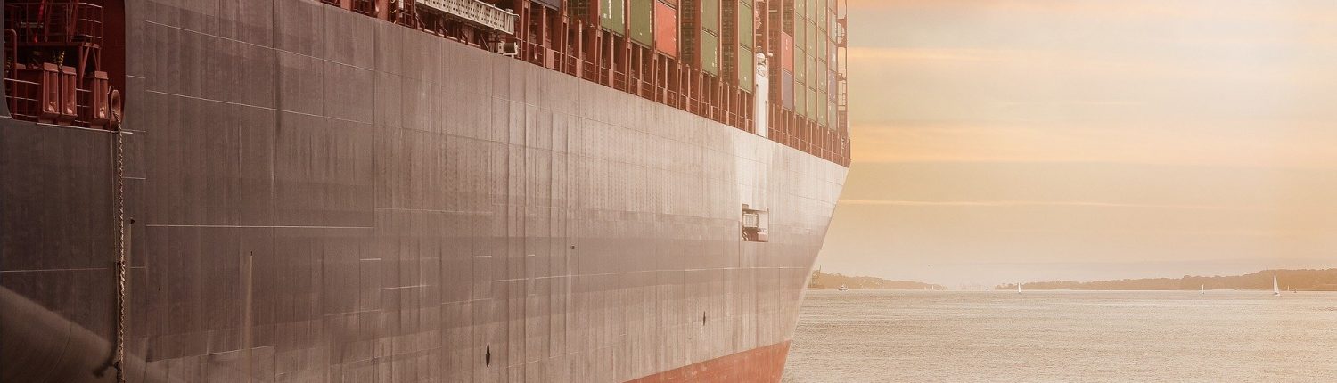 A shipping container on the water at sunset