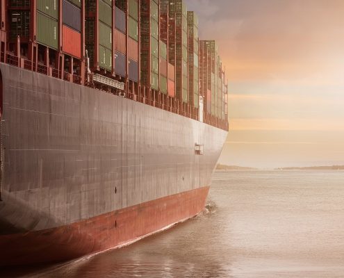 A shipping container on the water at sunset