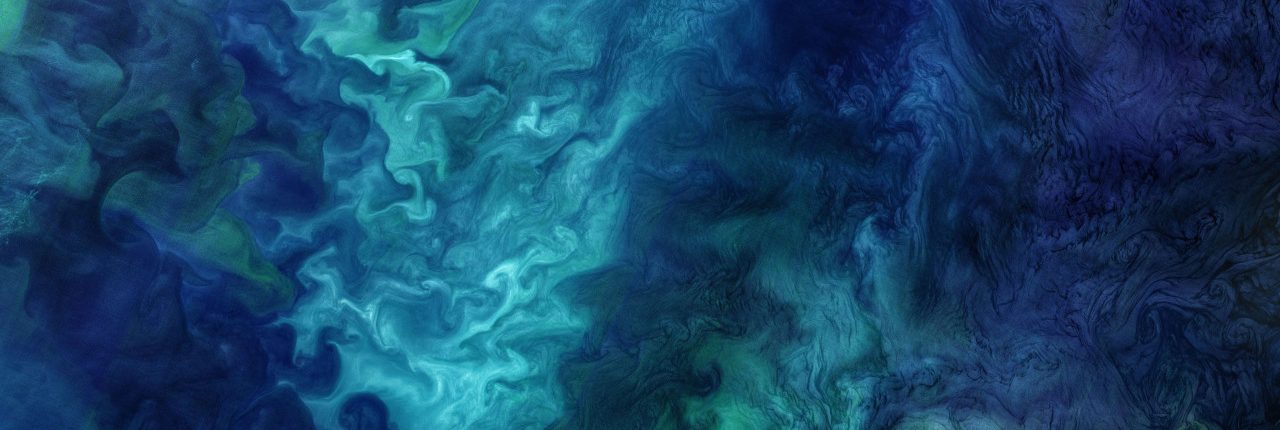 An aerial image of the ocean with swirling green and blue colors