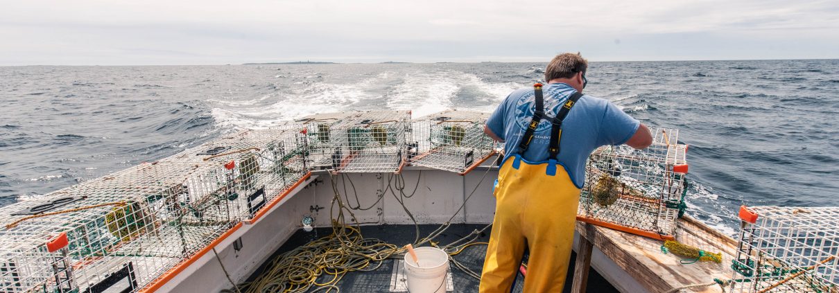 A deckhand on a lobster fishing vessel preparing equipment at sea.