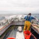 A deckhand on a lobster fishing vessel preparing equipment at sea.