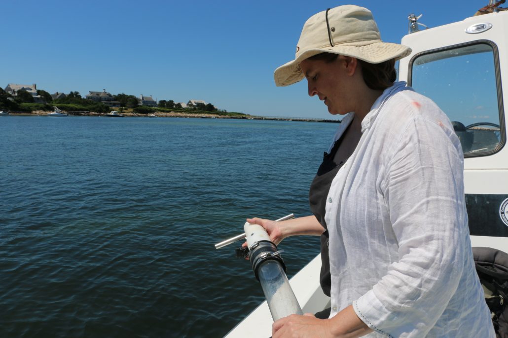 Dr. Juliet Simpson holds sediment core on a boat in Massachusetts.