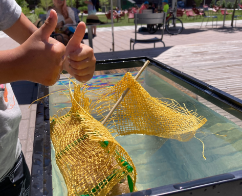 A young person showing the floating structure they built in a tank of water