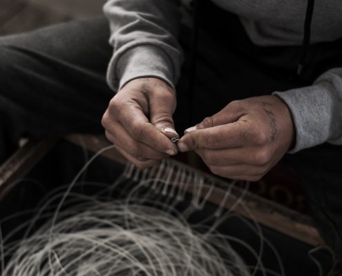 Two hands tying knots in fishing line